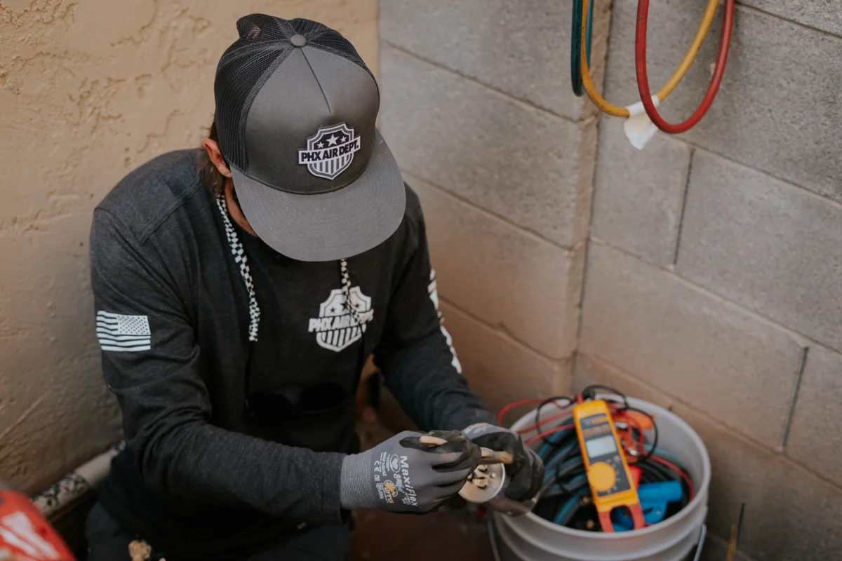 Technician testing an outdoor AC unit with diagnostic instruments